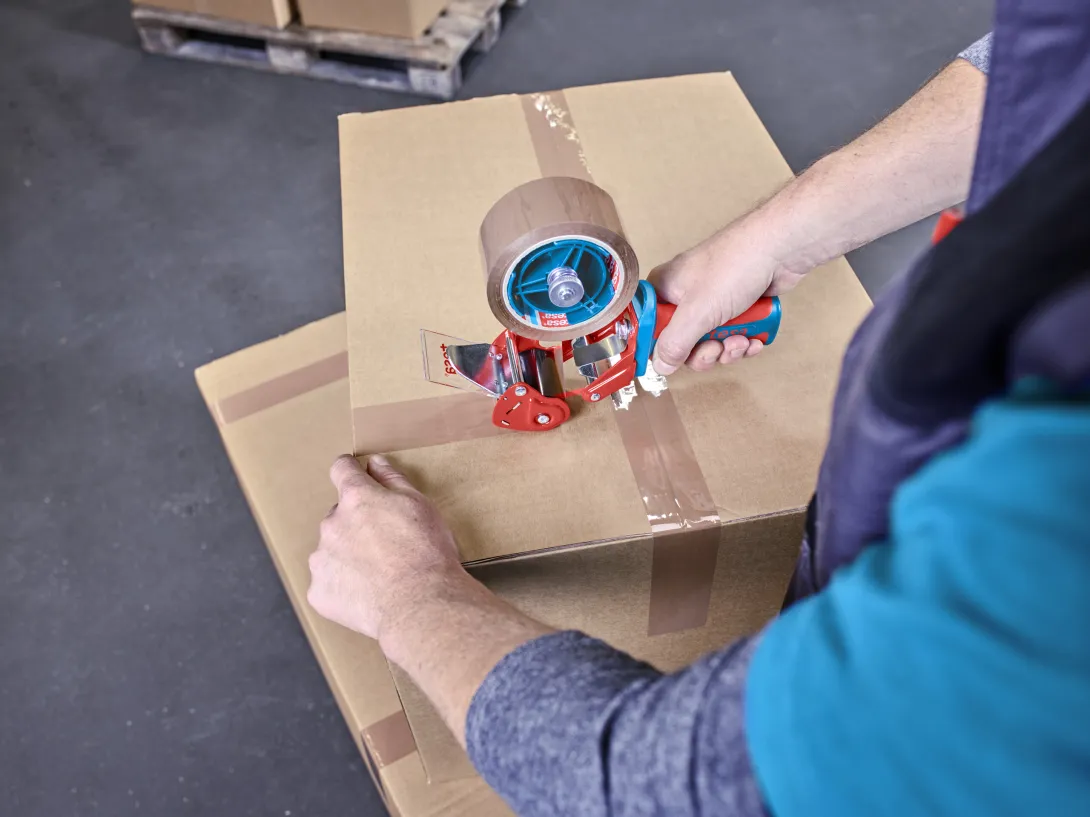 Utilisation du dévidoir manuel ergonomique Tesapack 6400 Comfort sur carton d’expédition