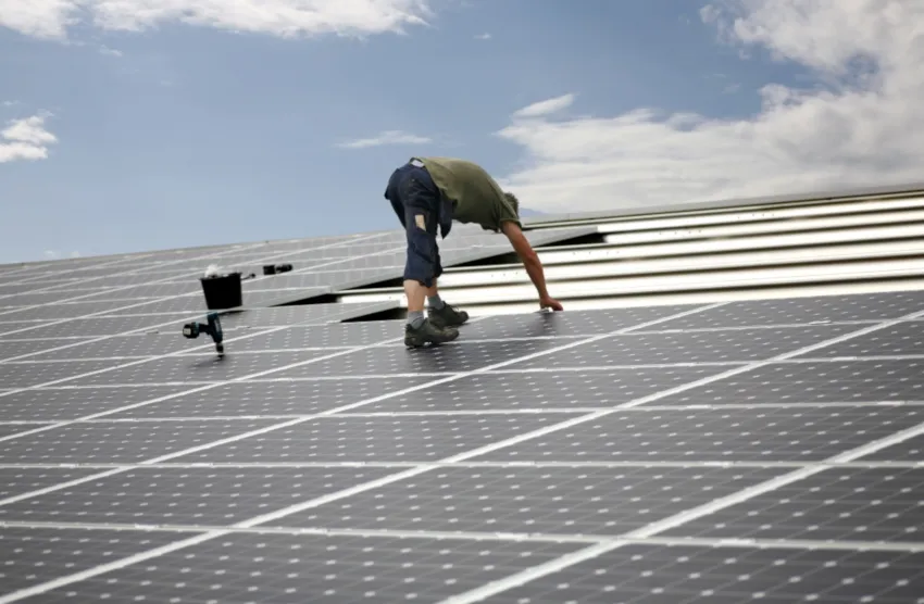 Panneaux solaires posés par une personne sur un toit en pente